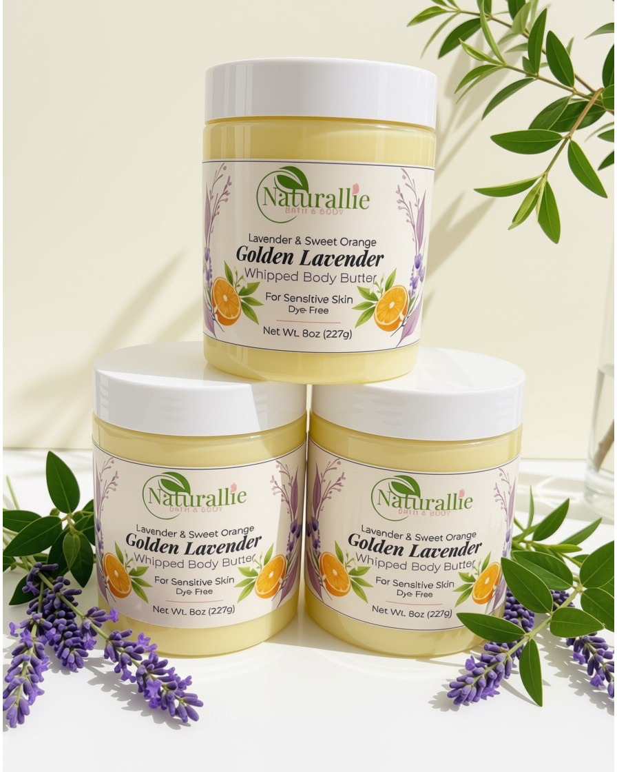 Three jars of Naturallie Golden Lavender Whipped Body Butter arranged in a pyramid on a white surface, decorated with green leaves and purple lavender flowers against a warm cream background.